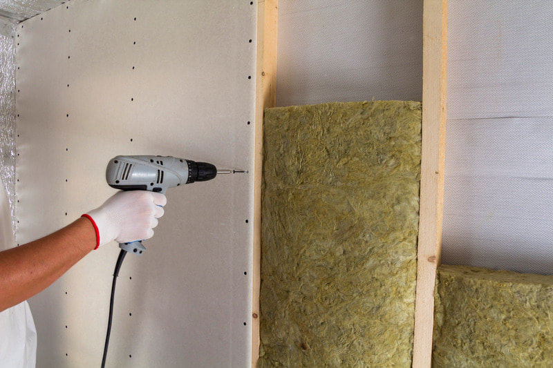 Screwing drywall into the studs. Insulation is already in place.