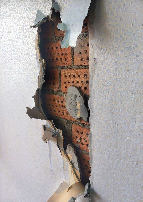 Drywall is peeling away and the brick underneath is currently exposed.